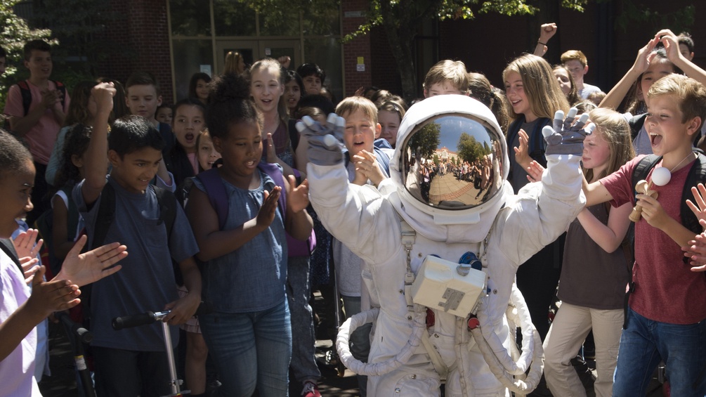 Winkendes Kind im Astronautenkostüm inmitten von Kindern