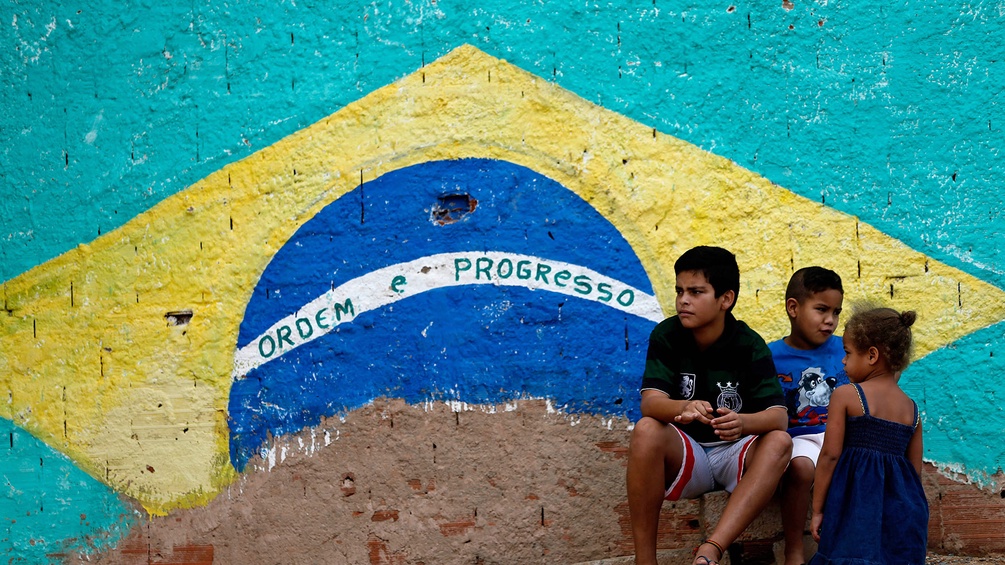 Kinder vor einer Hauswand, die mit der brasilianischen Flagge bemalt ist