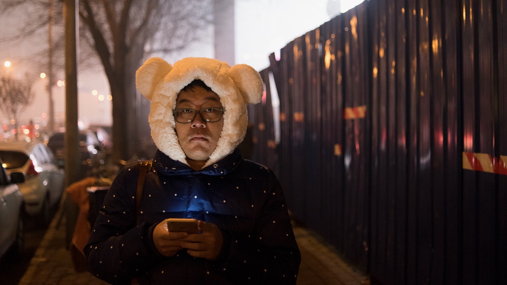 Mann mit Smartphone und Bärenhaube