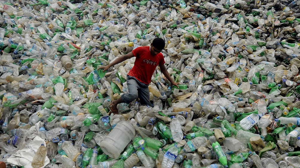 Ein Junge auf einer Halde von Plastikflaschen