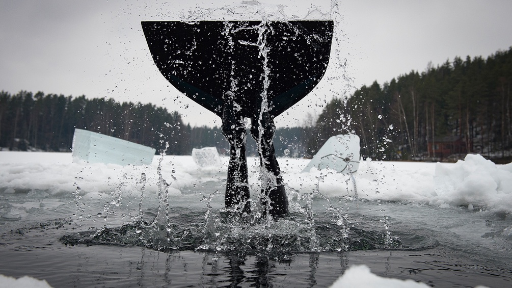 Freediving in Finnland - Sportlerin taucht in einen gefrorenen See