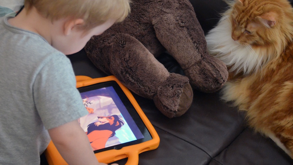 Kind mit iPad, Teddybär und Katze
