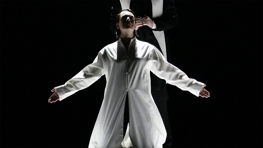 Opernszne: Frau in weißem Mantel
