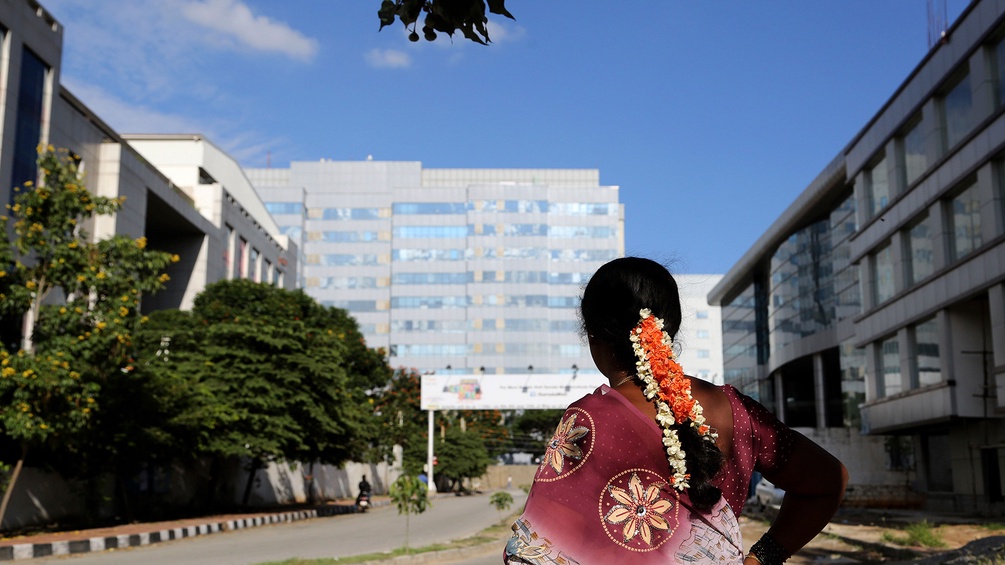 Eine Frau aus Indien steht vor IT-Gebäuden in Bangalore