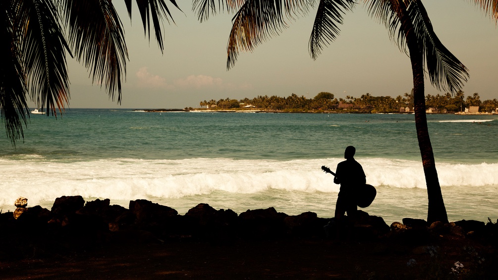Mann mit Gitarre am Strand von Hawaii