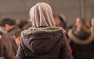 Flüchtlingsfrau mit braunem Kopftuch, von hinten
