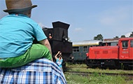 Kind sitzt auf den Schultern, schaut Züge an