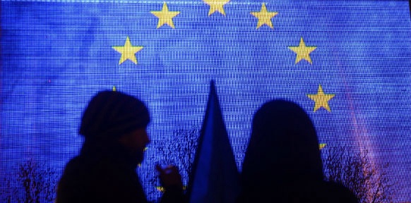 Zwei Menschen stehen vor einer EU-Fahne
