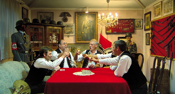 Männer um einen Tisch mit Nazi-Devotionalien