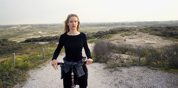 Frau am Strand auf einem Fahrrad