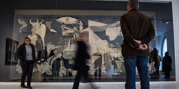 Menschen vor einer Tapisserie nach Picassos "Guernica"