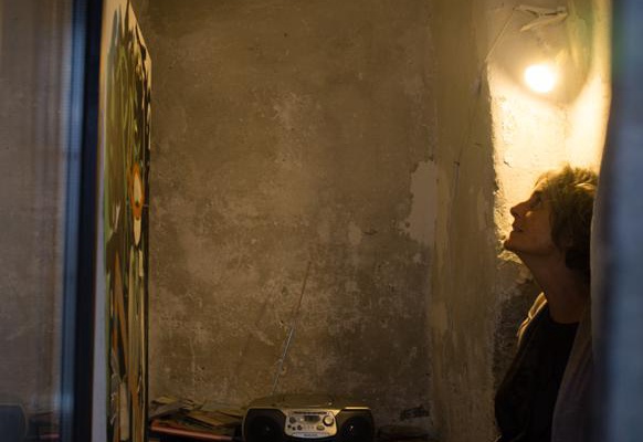 Eine Frau bestaunt ein Bild an der Wand, daneben ein Radiogerät.