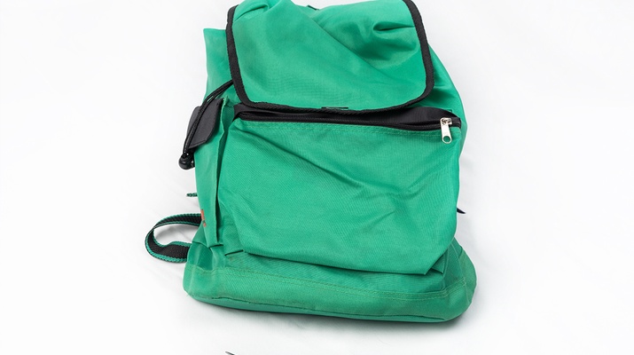 Ein grüner Rucksack, eine Gabel liegt davor