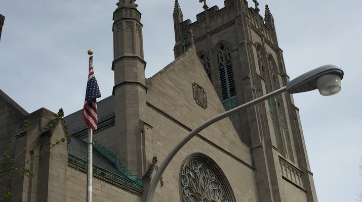 Portal der Kirche, davor weht die US-Flagger, verkehrt herum aufgehängt.