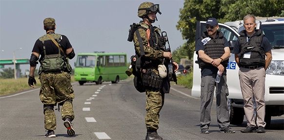 Bewaffnete Separatisten in der Ukraine nebst OSCE-Fahrzeug