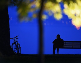 Blaue Stunde: Mann sitzt auf einer Parkbank