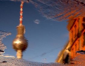 Der Berliner Fernsehturm spiegelt sich in einer Wasserlache