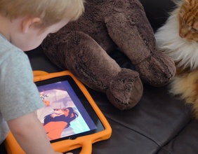 Kind mit iPad, Teddybär und Katze