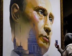 Eine junge Frau fotografiert in einem Museum ein Gemälde von Putin.