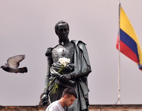 Straßenszene in Kolumbien mit Flagge, Taube und Statue