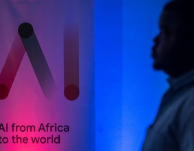 Ein Mann steht vor einem Banner der ersten Messe für künstliche Intelligenz in Afrika.