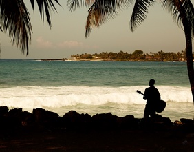 Mann mit Gitarre am Strand von Hawaii