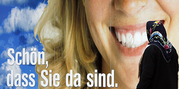 Eine Frau mit Kopftuch geht am Donnerstag (12.07.2007) in Berlin an einem Werbeplakat vorbei, 