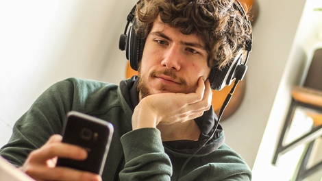 Junger Mann mit Handy und Kopfhörern
