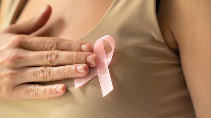 Weltbrustkrebstag: Frau hält rosa Masche an den Oberkörper