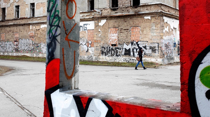 Alltagsaufnahme in Sarajevo, Frau geht an einer Ruine vorbei Graffiti