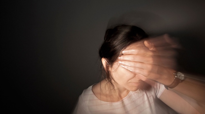 Frau hält sich Stirn