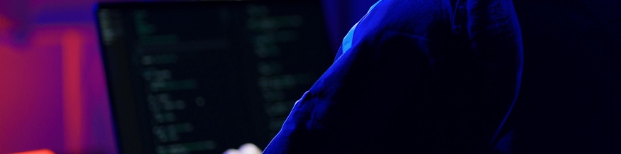 Mann in Hoodie vor Laptop