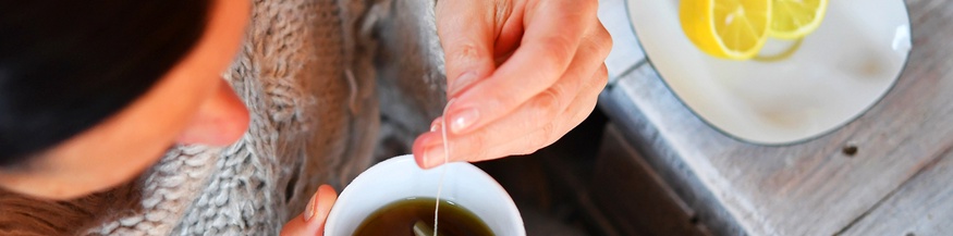 Eine Frau sitzt am Tisch mit Tee und Zitronen