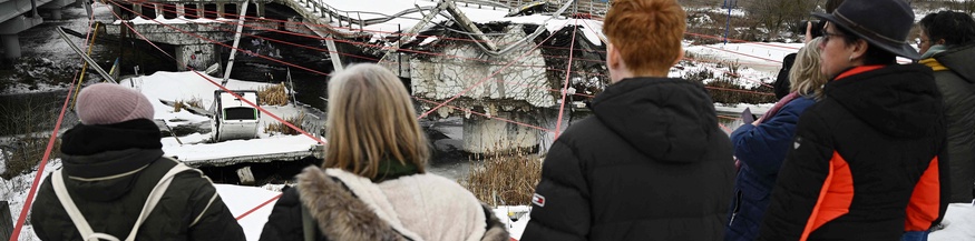 Menschen stehen in Irpin, Ukraine vor einer zerstörten Brücke