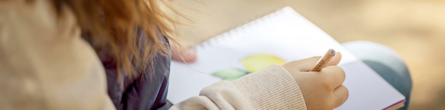 Ein Mädchen zeichnet im Freien