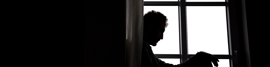 Ein Mann sitzt an einem Fenster.