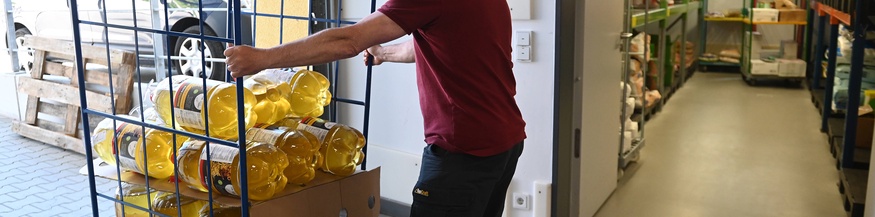 Arbeitender Mann rollt Ölflaschen hinaus, Liefereingang. Lieferung