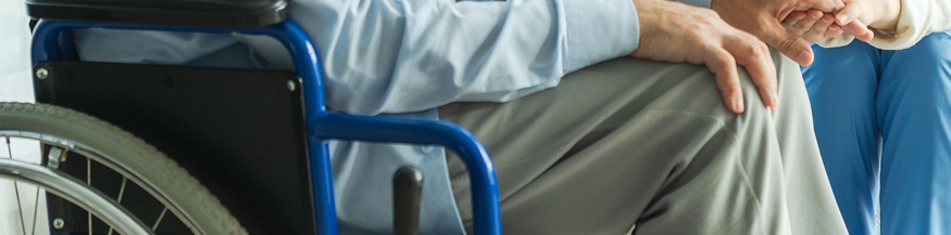 Mann im Rollstuhl und Pflegepersonal, tröstende Hände