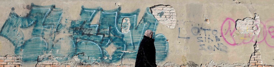 Frau mit Kopftuch vor einer Außenwand