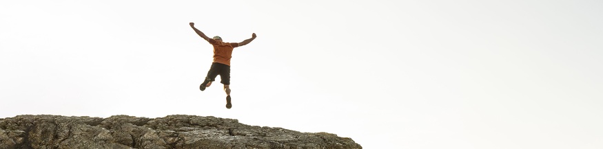 Mann springt von einer Klippe