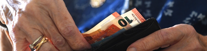 Ein Pensionistin öffnet ihre Geldbörse