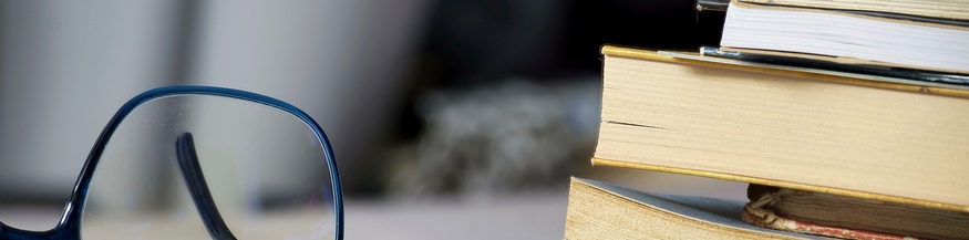 Brille neben Bücherstapel
