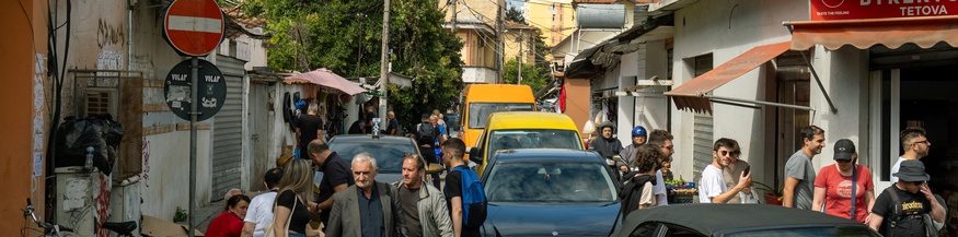 Auf einer Strasse in Tirana bewegen sich Menschen und Autos.