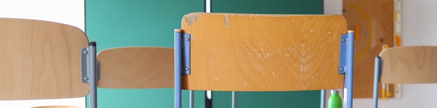 Klassenzimmer: Hochgestellte Stühle und Tafel