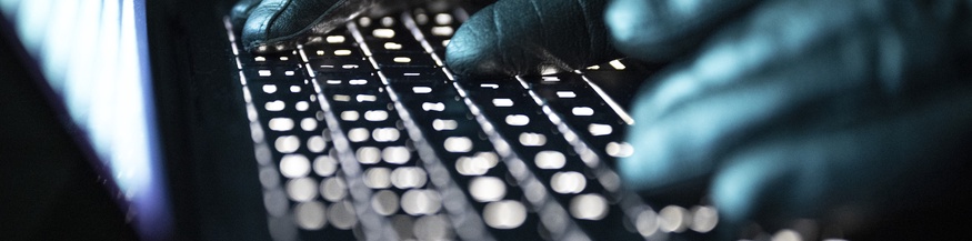 Hände in Handschuhen auf der Tastatur 