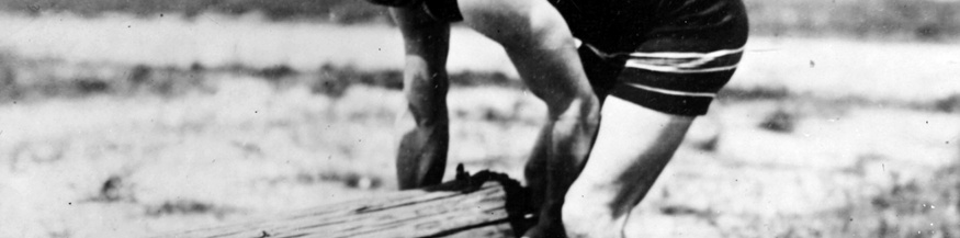 Boxer Jack Dempsey beim Training für die.Weltmeisterschaft: Heben eines.Baumstamms, um 1920