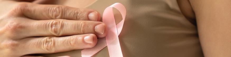 Weltbrustkrebstag: Frau hält rosa Masche an den Oberkörper