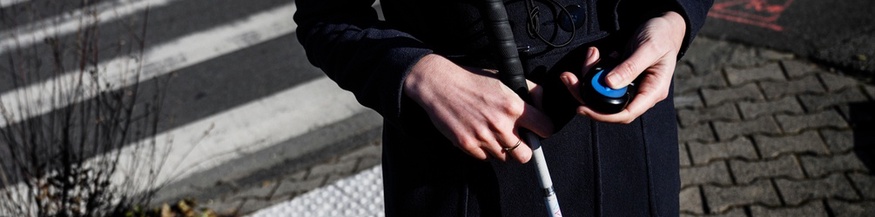 AFP/JEFF PACHOUD  Torso einer Person mit Blindenstock in der einen Hand, einem elektronischen Gerät in der anderen.