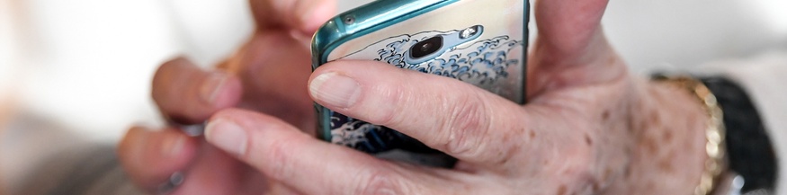 Die Hände einer älteren Dame mit einem Smartphone