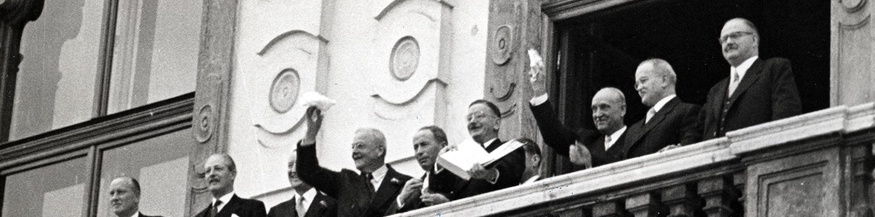  Leopold Figl (6.v.l.) zeigt am Balkon des Schlosses Belvedere den Österreichischen Staatsvertrag. Ebenfalls am Balkon, rechts neben Leopold Figl stehend: Adolf Schärf, Wjatscheslaw Michailowitsch Molotow, Julius Raab (v.l.n.r.). Außerdem sind Maurice Harold Macmillan (2.v.l.), John Foster Dulles (4.v.l.) u.a. zu sehen. 